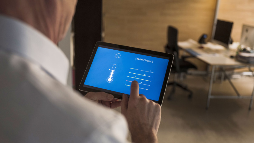 A person adjusting temperature through home automation app on tablet