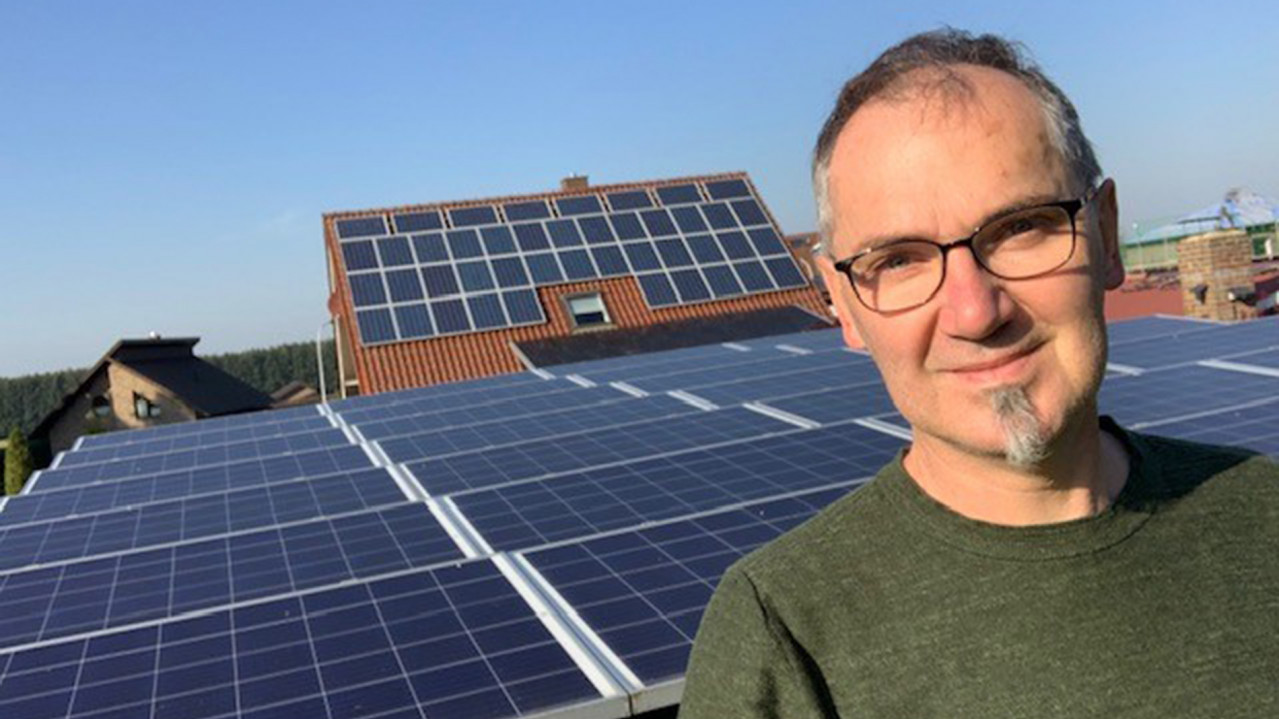 Botschafter Hans Schute auf seinem Dach, im Hintergrund sehen wir die PV-Anlage seines Daches.