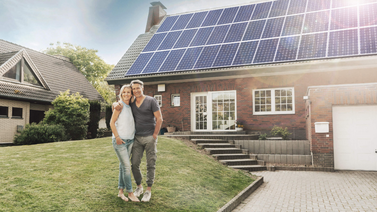 Image of couple on lawn in front of house with solar panels on roof