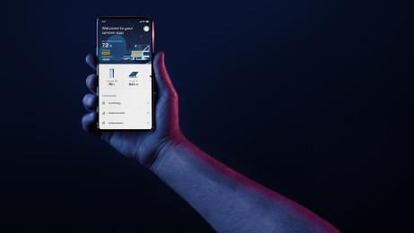 A picture showing a hand holding a phone at night. The phone is displaying the sonnen App in night-mode.