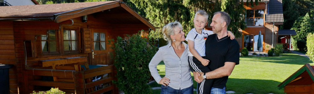 Mutter, Vater und Sohn im Garten vor dem Haus, zufriedenen sonnenBatterie Kunden