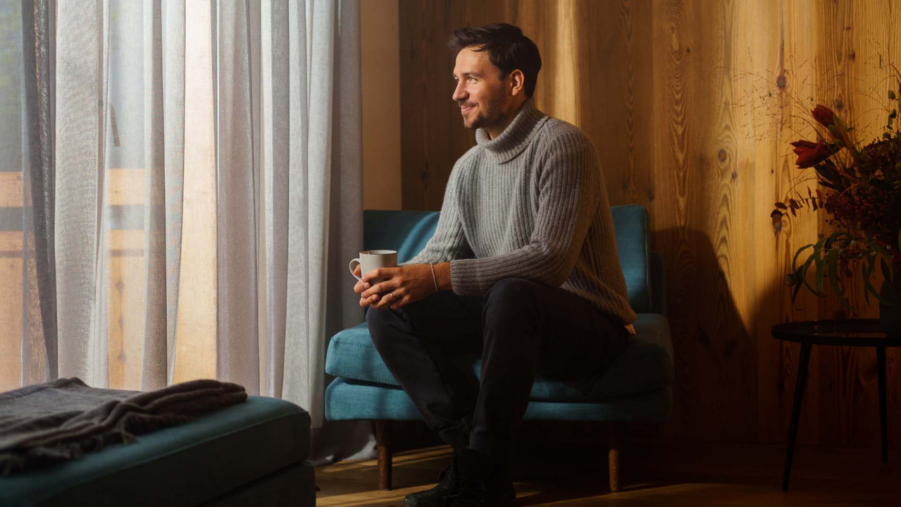 Felix Neureuther sitzt mit einer Tasse in der Hand auf einer Couch