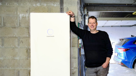 Een gelukkige sonnen klant staat naast zijn sonnenBatterie 10 in de garage.