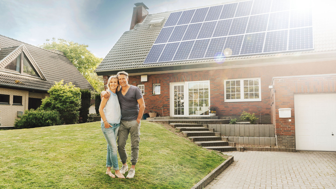 Paar vor ihrem Haus mit einer großen PV-Anlage