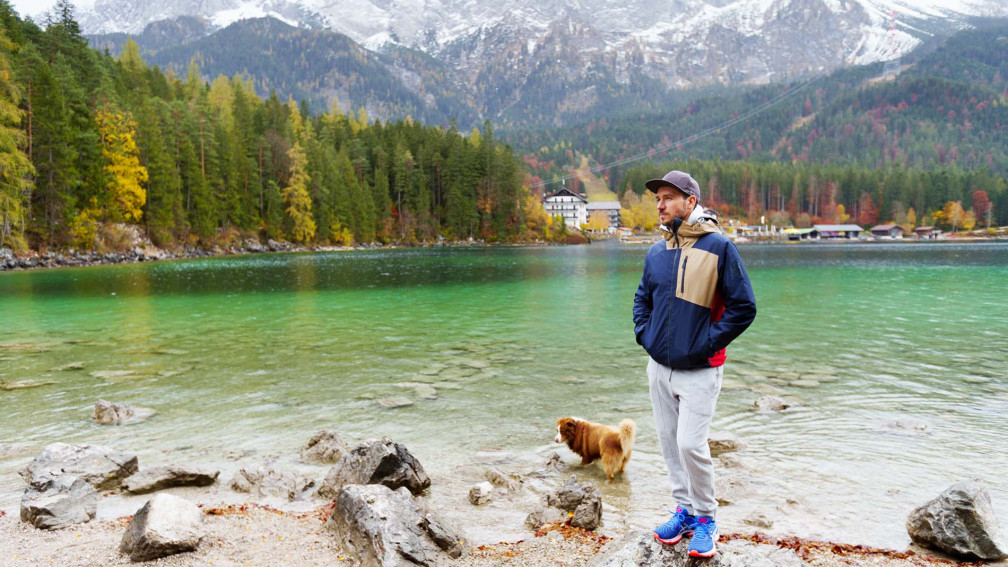 Felix Neureuther steht an einem See zusammen mit seinem Hund