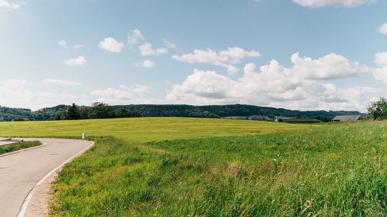 Feld im Technologiestandort Wildpoldsried mit einer großen Scheune im Hintergrund mit einer PV-Anlage auf dem Dach.