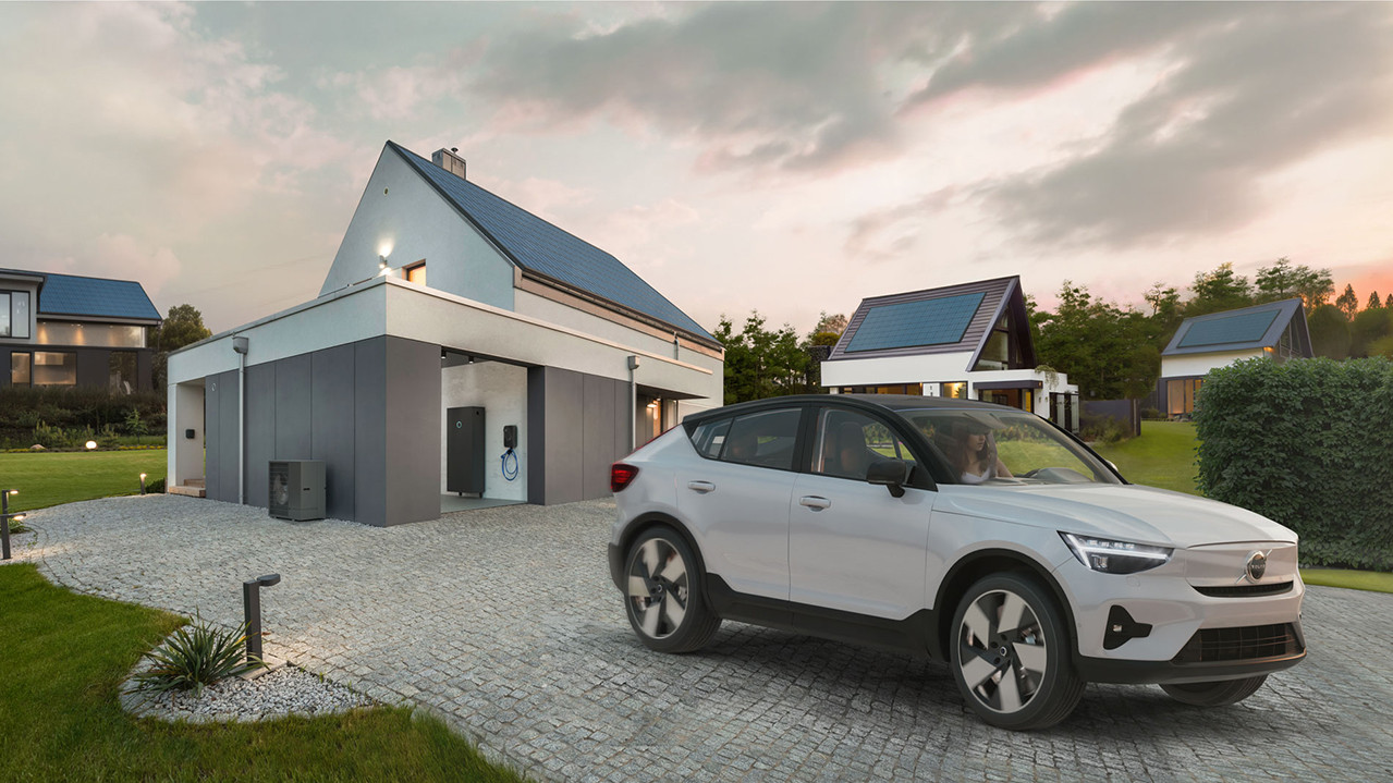 A photo showing a modern house with solar panels. The garage door is open and one can see the sonnen wallbox on the wall. An electric car is parked on the driveway. 