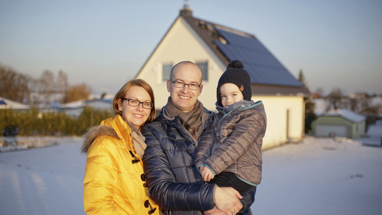 Familie Kaddatz steht vor ihrem Haus mit PV-Anlage