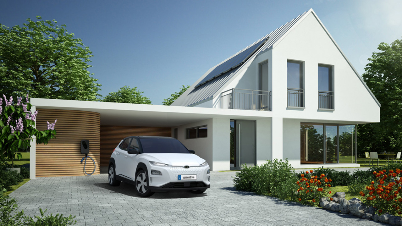 Kona Elektroauto steht vor einem Einfamilienhaus mit sonnenCharger in der Garage und PV-Anlage auf dem Dach